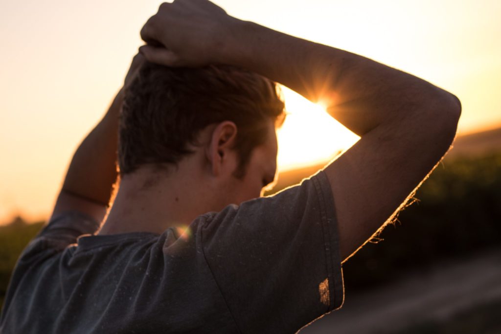 Young man standing outside at sunset